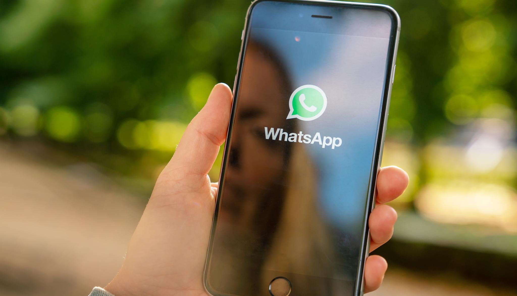 META bei WhatsApp Frau hält Handy mit WhatsApp Logo in der Hand